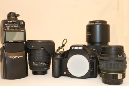 Pentax K200 (PS! Mulig defekt, batteriindikator blinker) med 3 objektiver (1. Pentax 55-300 SMC/DA 1:4-5.8,  2. Sigma 20mm 1:1.8 EX DG Aspherical,  3. Pentax 18-55 II SMC/DA), blitz (Pentax AF-540FGZ) og veske. Kamerahus bruker 4 LR6-batterier, ingen lader medfølger Kontakt Lånekontoret for frakt