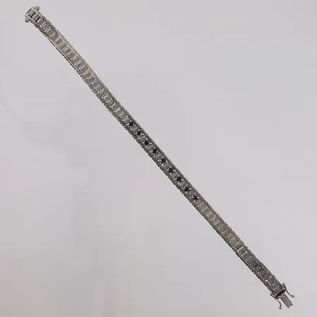 Armbånd med 9 blå-sorte stener, lengde 19,5cm, bredde 7mm, noe defekt mønster, hvitt gull, 14K Vekt: 20,9 g Kontakt Lånekontoret for frakt