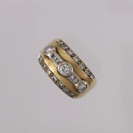 Ring med briljantslipte diamanter (1 x ca. 0,23ct + 2 x ca. 0,16ct + 18 x ca. 0,01ct), to-farget, ø16,7mm, bredde 5,6- 12,2mm, 18K Vekt: 15,1 g Kontakt Lånekontoret for frakt