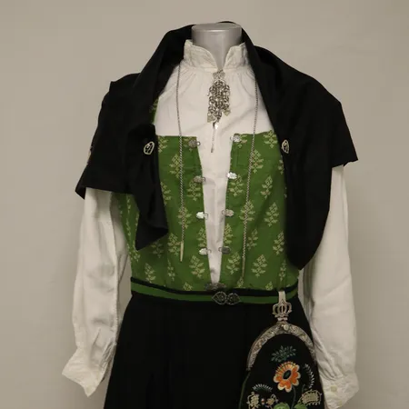 Østfold-bunad med skjorte, belte, veske, sjal, sølvkjede, en sølje og to sjalnåler. Hel lengde 128cm, skjørtelengde 82cm, Livvidde 85cm,  (ca. strl. 38/40).  Vekt: 0 g Kontakt Lånekontoret for frakt