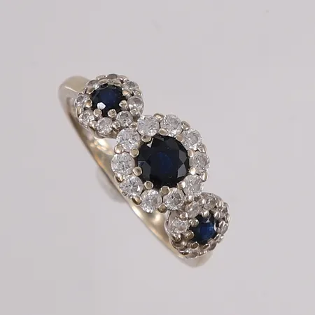 Ring med diamanter (10 x ca. 0,035ct + 15 x ca. 0,01ct) og 3 mørk-blå stener, Thune, ø16,5mm, bredde 2- 8,9mm, én sten mangler, gravert, hvitt gull, 14K, bruttovekt 3,1g Vekt: 0 g Kontakt Lånekontoret for frakt