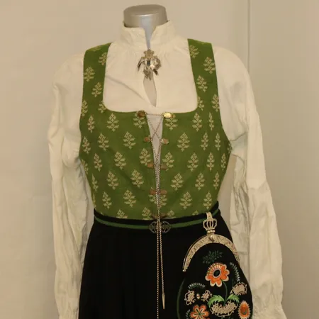 Østfold-bunad (dame, ca. str. 38/40) med skjorte, sjal, lue, veske, kjede, én sølje, 2 sjalnåler og ett par øredobber. Hel lengde 140cm Kontakt Lånekontoret for frakt