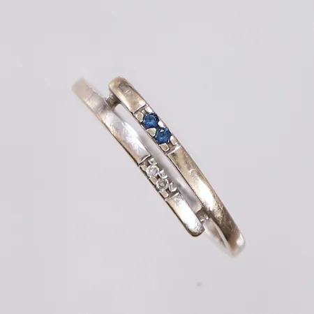 Ring med 2 diamanter (totalt 0,01ct iht. gravering) og 2 blå-sorte stener, ø16,5mm, bredde 1,6- 3,8mm, hvitt gull, 14K, bruttovekt 1,3g Vekt: 0 g Kontakt Lånekontoret for frakt