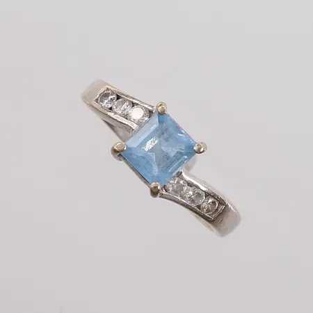 Ring med diamanter (6 x ca. 0,04ct) og lys-blå sten, ø17,5mm, bredde 2,8- 7,7mm, hvitt gull, 18K, bruttovekt 5,3g Vekt: 0 g Kontakt Lånekontoret for frakt
