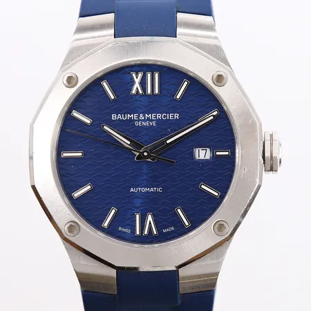 Baume & Mercier Riviera, ref. M0A10619, snr. 6158317, ø42mm, stål, automatisk, blå urskive, safirglass, blå gummi-rem med dobbel foldelås, romertall, dato, noe slitasje. Med boks, manual og garantikort (kjøpt hos Urmaker Larsen 26.09.2022) Vekt: 0 g Kontakt Lånekontoret for frakt