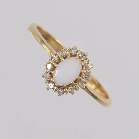 Ring med 12 stk. briljantslipte diamanter (totalt 0,12ct iht. gravering) og én syntetisk opal, ø17,9mm, bredde 1- 9,3mm, 14K, bruttovekt 2g Vekt: 0 g Kontakt Lånekontoret for frakt