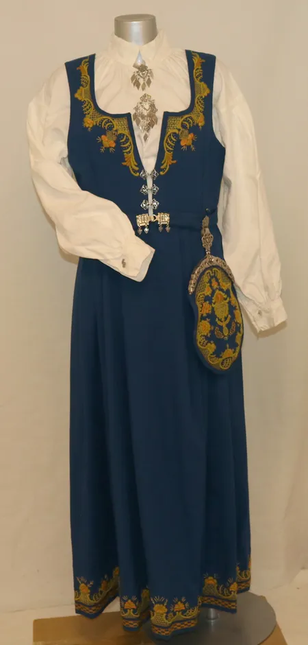Romeriksbunad dame (ca. str. 38) med skjorte, veske, belte, 2 stk. søljer, ett par øredobber og ett par mansjettknapper. Hel lengde 137cm, liv-vidde 90cm. Vekt: 0 g Kontakt Lånekontoret for frakt