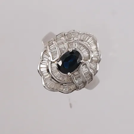 Ring med sannsynligvis safir og baguetteslipte diamanter totalt 1,15ct iht gravering, ø17mm, bredde ca 3mm, 18K hvitt gull. Vekt: 8,3 g Kontakt Lånekontoret for frakt