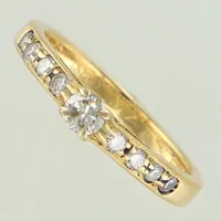 Ring med diamanter, ca 1x0,14ct samt 8x0,02ct, stl 16, bredd ca 2-3mm, gravyr. 18K  Vikt: 2,7 g