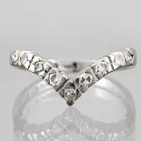 Ring, 18K vitguld, Diamanter 9 x 0,02ct - stämplad 0,18 på insidan av skenan, v-formad modell, tillverkarstämpel SSÄ, svensk kontrollstämpel, Ø15,0 mm, skenans bredd 1,7 - 2,3 mm Vikt: 2 g