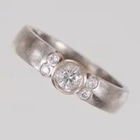 Ring stl 15½, bredd 3,9mm, diamanter 1x ca 0,18ct, 4x ca 0,01ct, gravyr, vitguld 18K Vikt: 4,6 g