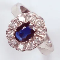  Ring i karmosémodell med oval mörkblå safir ca 0,80ct, samt briljantslipade diamanter 10 x ca 0,05ct, totalt 0,50ct enligt gravyr, kvalitet ca W(H)/SI, stl: 16, tillverkad av Guldfynd AB, 18K Vikt: 5 g
