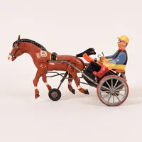 Mekanisk leksak, jockey med häst, plåt samt plastliknande material, längd 17cm, 1900-talets första hälft, Tyskland, slitage, piska av, uppdragningsarm saknas.  delar saknas Vikt: 0 g