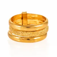 Thai: delvis glitterslipad, tredelad ring i 23K guld. Den är 10,5 mm bred, är i storlek c:a 19½ och väger 7,6g (½ baht). Stämplad 96,5%. 