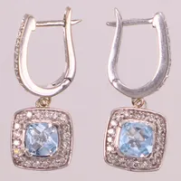 Ett par örhängen med fasettslipade blå topaser och briljantslipade diamanter totalt 0,35ctv, längd 23mm, GHA, vitguld 18K Vikt: 4,8 g