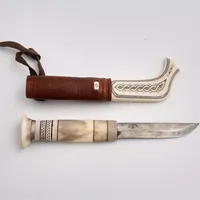 Samekniv i graverat horn och läder, tillverkad av Ingvar Backlund, år 1986, knivblad 10cm, total längd 23cm.