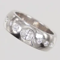 Ring med diamanter, oval briljantslipad diamant 1x ca 0,65ct ca W/SI, samt rund briljantslipade diamanter 6x ca 0,05ct, stl 19¼, bredd 8,3mm, vitguld, Schalin 18K  Vikt: 19,8 g