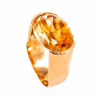 Härlig ring i 18K guld med en oval, orange sten. Graverat mönster på undersidan av fattningen. Stenen sticker upp 10 mm från fingret. Den är 4,7 - 12 mm bred, är i storlek 15¾ och väger 8,8g. Stockholms stadsstämpel, kattfot, 18K & S9 (1968). Signaturstämplad Stigbert.  