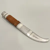 Samekniv med skaft i ben, slida i ben samt läder, blad av Paul Larsson, längd: ca 28cm, bladets längd: ca 13cm