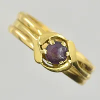 Ring med lila sten tillverkad av äldre vigselringar samt gravyrer, stl 17¾, 18K.  Vikt: 5,4 g