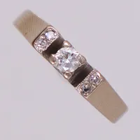 Ring med briljantslipad diamant 1x0,13ct samt åttkantslipade 4x0,01ct, stl 16½, höjd 6mm, Malmö, år 1974, vitguld 18K Vikt: 3,5 g