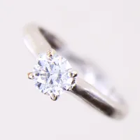 Ring med briljantslipad diamant 1 x ca 0,62ct Tcr(I-J)/P, stl: 15¾, bredd 2,3mm, gravyr, vitguld 14K.  Vikt: 2,9 g