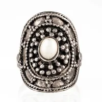 Ring i silver med en pärlemovit sten. Den är 3 - 26,7 mm bred, är i storlek 19 och väger 7,5g. Stämplad 925.