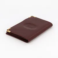 Korthållare/plånbok Cartier i mörkrött skinn med förgyllda detaljer, Must De Cartier, 10x7x0,8cm, referensnummer 73184147, med duk i original ask