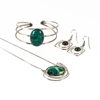 Set i silver med grönfläckiga stenar: collier (41,5 cm lång, 1- 30 mm bred), krokörhängen (40 mm långa) & armband (7 - 25 mm brett, innermått 14,5 cm + 1 cm öppning). De väger 35,6g tillsammans. Stämplade 925.