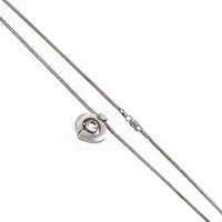 Finnfeelings: hjärtformad berlock i silver med bergskristall. Den är 21,4 x 19 mm. Design Karl Laine. En 45 cm lång ormlänk i silver medföljer. Karbinhake. De väger 11,4g tillsammans. 