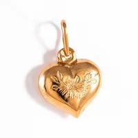 Berlock "hjärta med blomsterdekor" i 18K guld. Slät baksida. Den är 19,4 mm lång inkl. ögla och väger 0,6g. Stämplad 750.