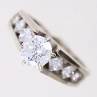 Ring med diamant, briljantslipade ca 1,00ct kvalité ca W(H)/P, samt 8xca 0,02ct, prinsesslipade 2xca 0,25ct, 2x ca 0,16ct samt 2x ca 0,12ct, stl 17¾, bredd 3 - 6,5mm, vitguld, ostämplat, 14K Vikt: 5,5 g