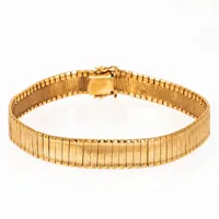 Halvstelt armband i 18K guld. Det är 19,2 cm långt, 9,5 mm brett och väger 25,8g. Kistlås. Ojämnt.