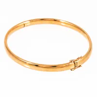 Öppningsbart, stelt armband i 18K guld. Det är 5 mm brett, har ett innermått på 17,5 cm och väger 7,9g. Kistlås. 