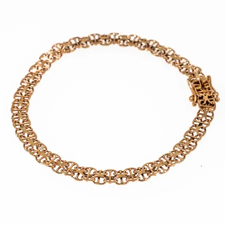 Armband x-länk i 18K guld. Det är 18,5 cm långt, 5,2 mm brett och väger 6,1g. Kistlås. Tillverkat 1987 av NSE Guldvaru Aktiebolag i Köping. Kattfot.