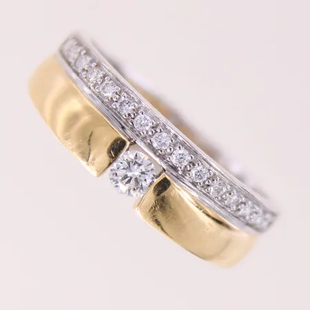 Ring med brljantslipade diamanter 1 x ca 0,16ct, 15 x ca 0,01ct, stl: 18½, bredd 4,7-6,8mm, GHA, vit/gult guld 18K.  Vikt: 6,4 g