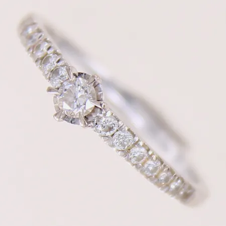 Ring med briljanterade diamanter 1 x ca 0,12ct, 14 x ca 0,01-0,02ct, stl: 18½, bredd 1,3-5mm, GHA, vitguld 18K.  Vikt: 2,6 g