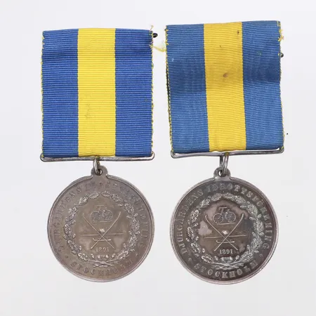 2 medaljer, silverfärgade, Djurgårdens Idrottsförening, gul/blå ripsband, ograverade. Föreningen bildades i Stockholm 1891.