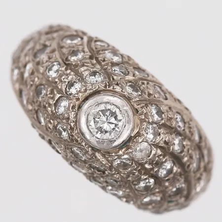 Ring med diamanter 53 x ca 0,015ct samt 1 x ca 0,10ct, stl: 15½, bredd: 4-10mm, 18K vitguld. Vikt: 9,1 g