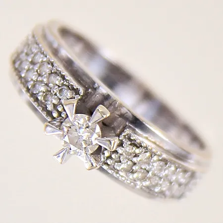 Ring med diamanter 1 x ca 0,18ct 24 x ca 0,005ct, stl 15½, bredd 3,7-6,1mm, vitguld, 18K Vikt: 4 g