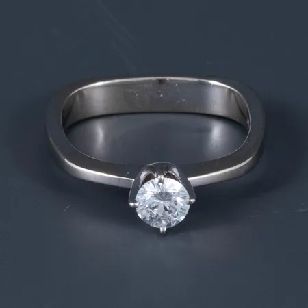 Georg Jensen: ring i vitt guld 18K med en briljant 0,31ct (River - vvs enligt medföljande certifikat). Den är 3,3 - 5,7 mm bred, är i en storlek som motsvarar c:a 17 på en rund ring och väger 3,4g. Stämplad GJ&W 750. Originalkvitto från 1979 medföljer. 