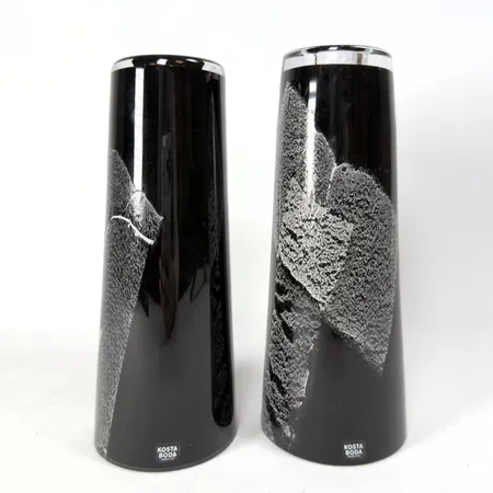 Ett par ljusstakar/vaser, Anna Ehrner, Kosta Boda, underfång i lila med vit och grå dekor, signerade Kosta Boda A Ehrner 7060801, även etikettmärkta, höjd 19 och 20cm Skickas med paket.