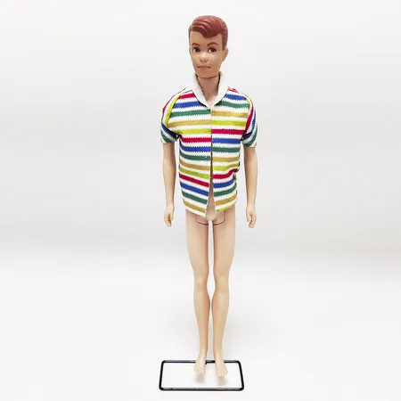 Barbiedocka, #1000 Allan, tillverkad år 1964, märkt "©1960 by Mattel Inc. Hawthorn Calif. U.S.A.", Kens kompis som delar kroppsform och märkning med Ken men har egen huvudform och kläder, denna Allan är endast klädd i strandjacka med horisontella ränder, han saknar blå bomullsshorts och korktofflor, inga övriga tillbehör. Vikt: 0 g
