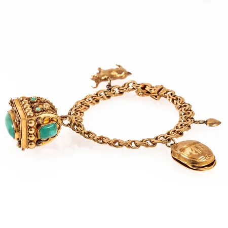 Armband bismarck i 18K guld med fyra berlocker; bla. en öppningsbar ask med turkosa stenar. Det är 19 cm långt, 7,8 mm brett och väger 50.1g BTO. Tillverkat 1962 av Ahlms Guld & Silververkstad i Stockholm.