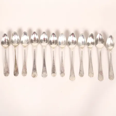 Tolv skedar, snarlika modeller, varierande längder: 138 - 147 mm, olika tillverkningsår och tillverkare, gravyr, silver. Vikt: 118,9 g