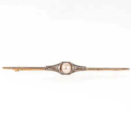 Brosch i 18K röd- och vitguld, med odlad vit halvpärla Ø 6 mm och två små rosenslipade diamanter á c:a Ø 1 mm. Den är 1,3 - 7,7 mm bred, 74 mm lång och väger 3,3g inklusive pärla. Stämplad ABH (Bernhard Hertz Aktiebolaget, Stockholm), 18K & Kattfot.