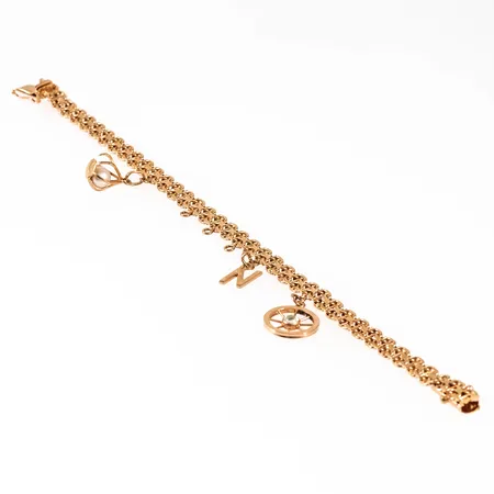 Armband X-länk med stav i 18K guld. 3 berlocker: Livets hjul, N, korg med pärla. Det är 6 mm brett, 19 cm långt och väger 15,0g inklusive pärla och sten. Kistlås. Stämplad O9 (1964), SR (Segir AB, Köping), 18K & Kattfot. Tre pålödda öglor utan berlocker.