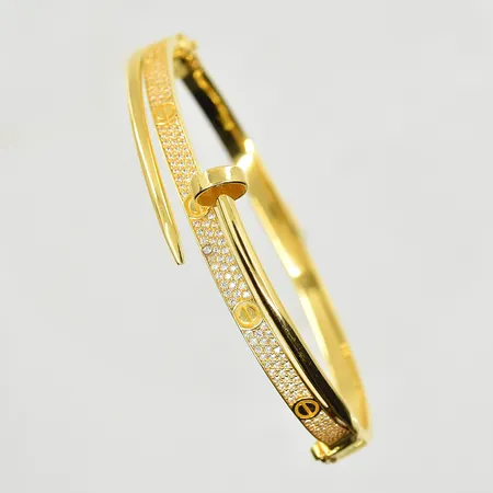 Armring med vita stenar, oval modell, innermått 60x50 mm, bredd 4-14 mm, en sten utbytt, Obs Ej märkesdesign, 21K. Vikt: 13,6 g