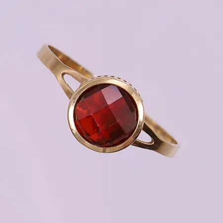 Ring med röd fasetterad sten, stl: 19, bredd 1,5-8,5mm, skev, ostämplad 18K.  Vikt: 1,7 g