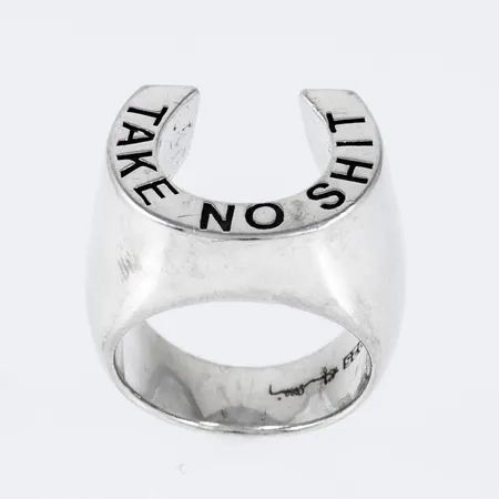 Ring "Take No Shit" i silver (925/1000). Formad som en hästsko. Den är 6,5 - 15 mm bred, är i storlek 16½ och väger 17,1g. Design: Efva Attling. Originalask medföljer. Nypris 5400:-